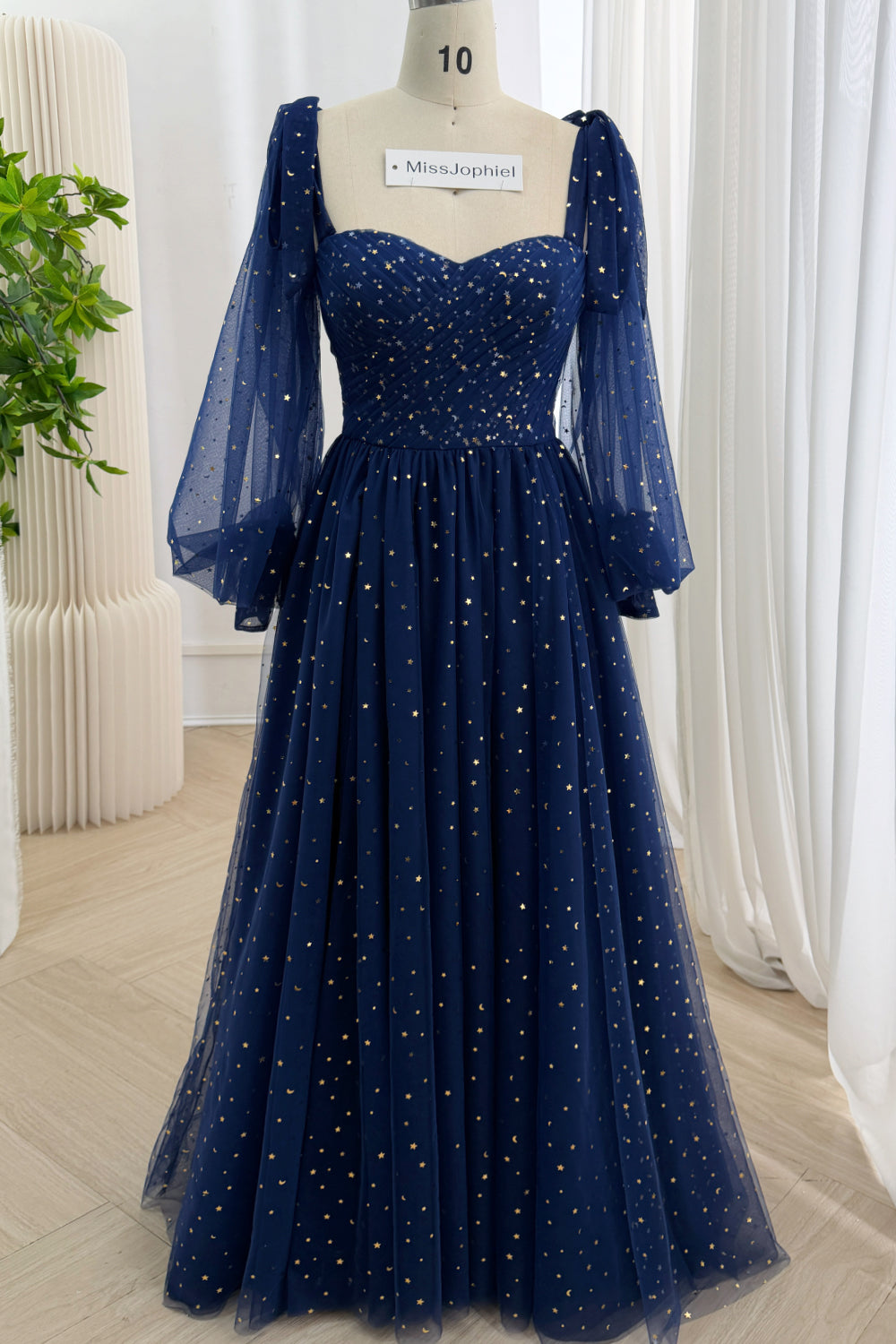 Front view of a dark navy floor-length prom dress covered with metallic stars and crescent moons