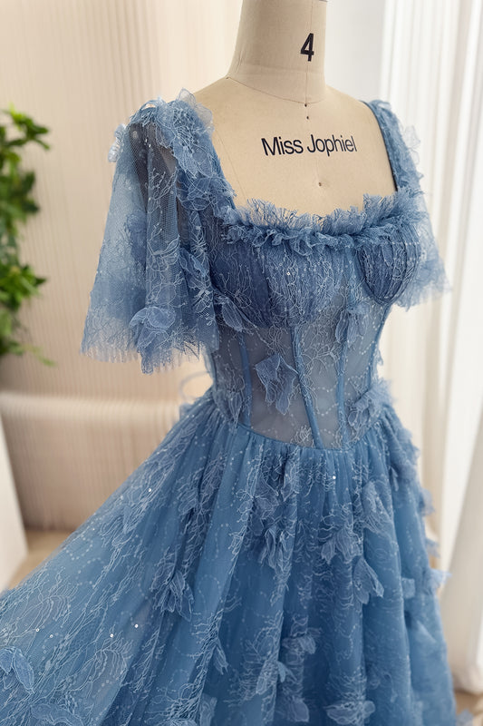 Angled close-up of dusty blue floral lace gown with ruffled square neckline, sheer flutter sleeves, and boned corset bodice.
