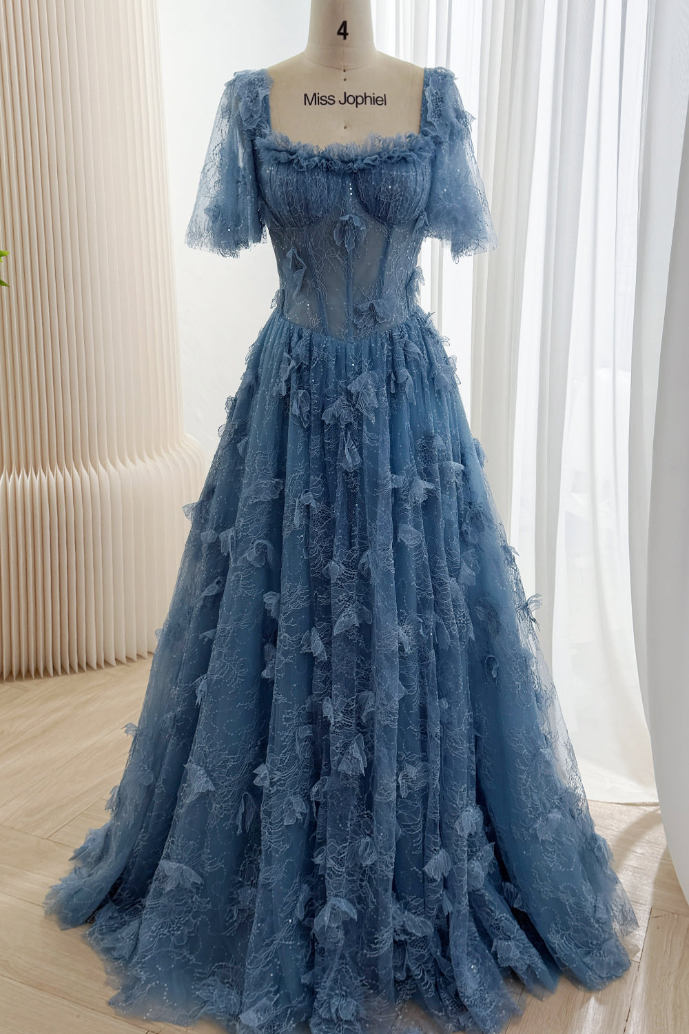 Full front view of dusty blue floral lace corset gown with a square neckline, sheer flutter sleeves, and a full A-line skirt.