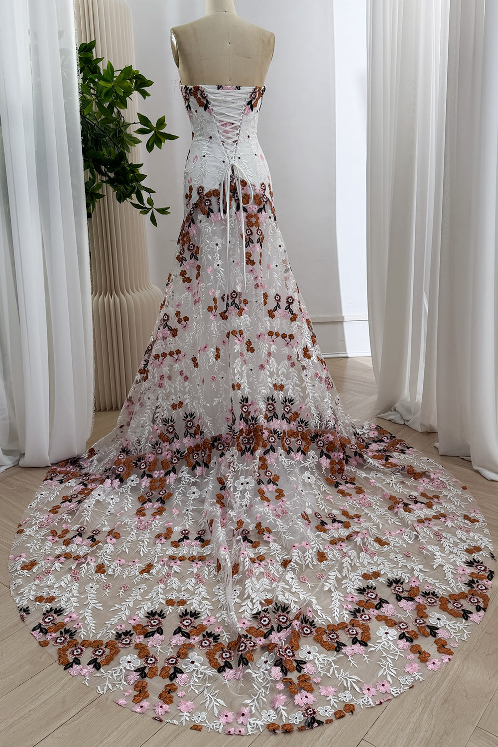 Back view of the floral embroidered wedding dress with a lace-up corset closure and sweeping train