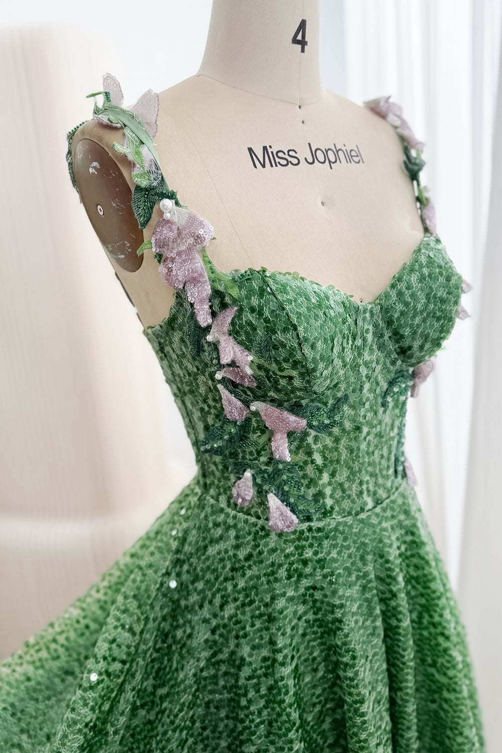 Close view of sweetheart neckline, green sequins and pink floral appliqués