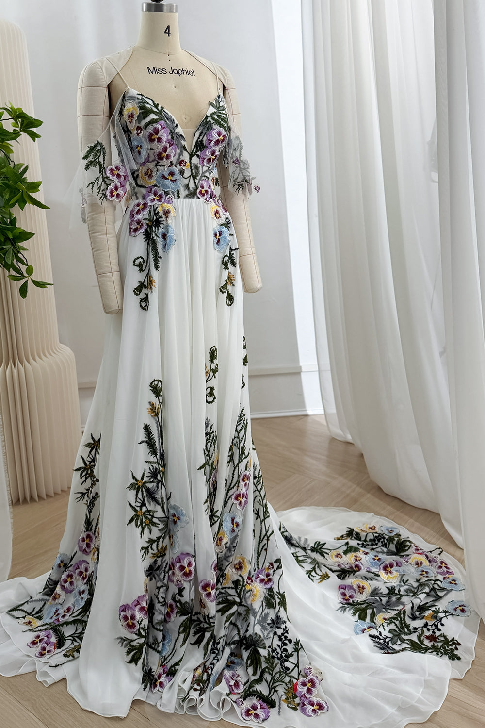 Angled front view of the ivory floor-length gown with botanical embroidery concentrated along the bodice and hem