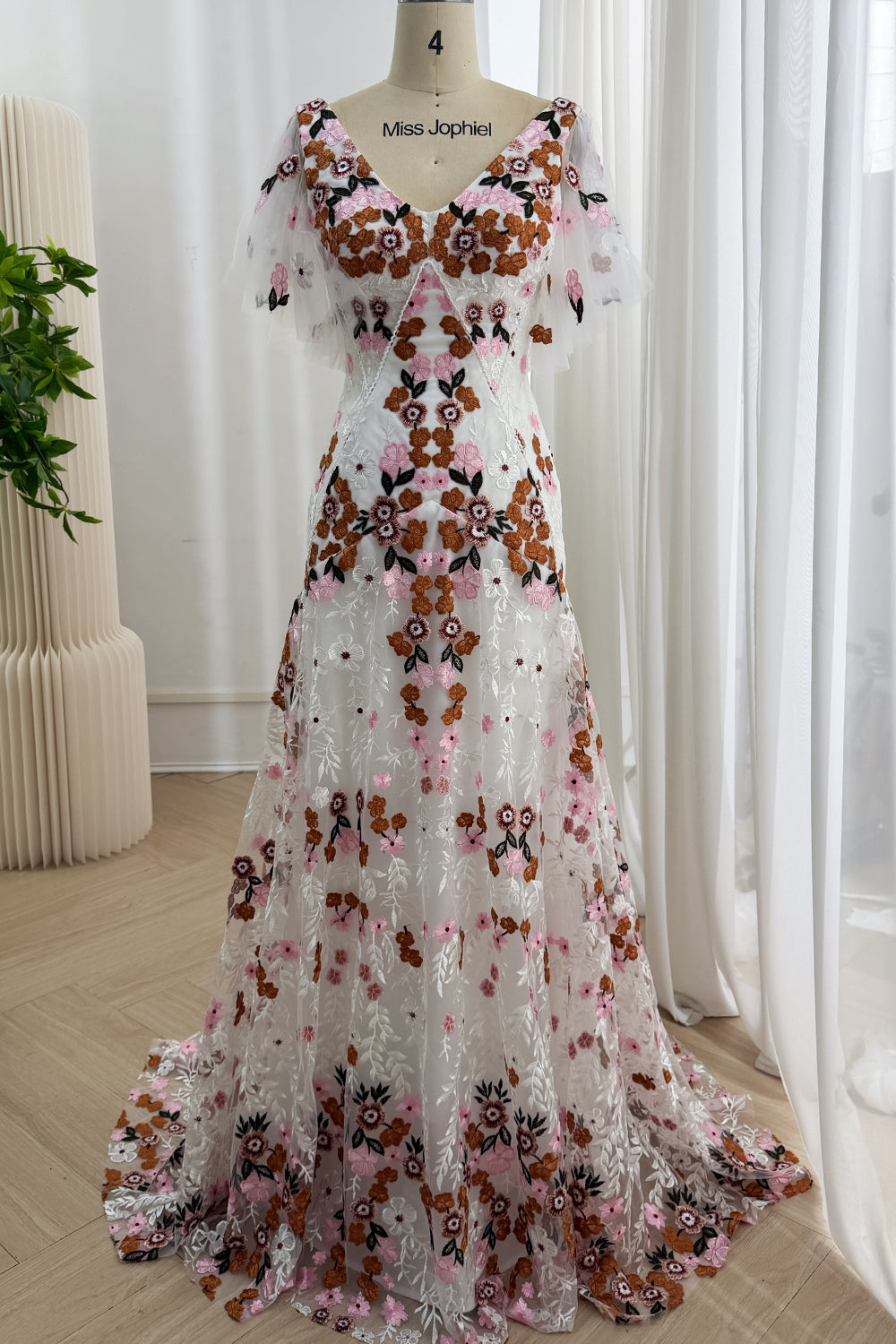 Full front view of the ivory A-line gown with multicolor floral embroidery and flutter sleeves