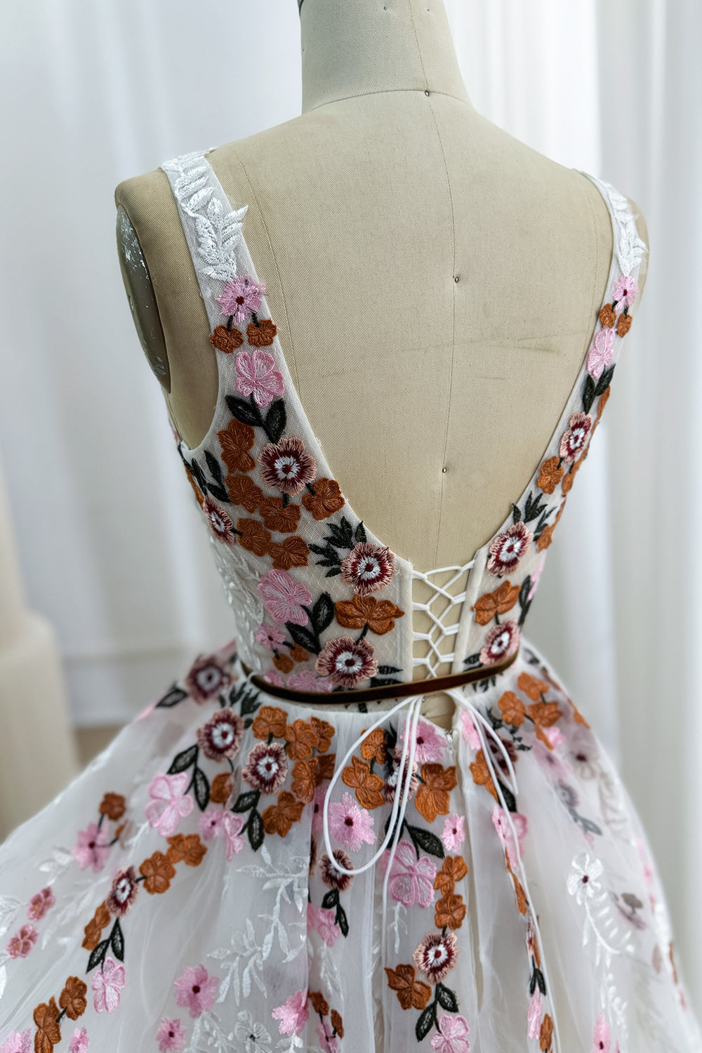 Back bodice detail of the ivory floral embroidered dress with a low V-back and white corset lacing