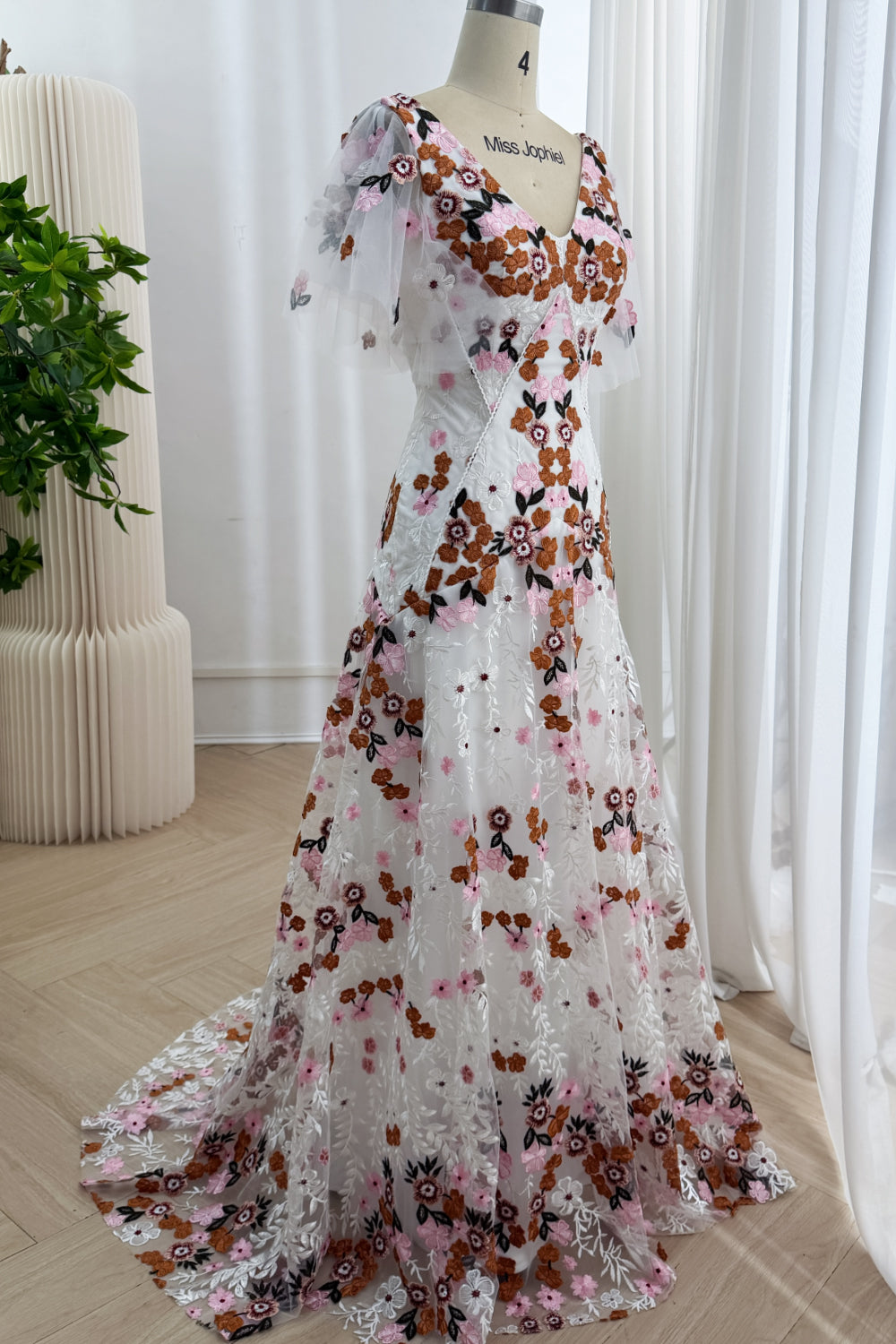 Angled side view of the ivory multicolor floral embroidered floor-length A-line gown