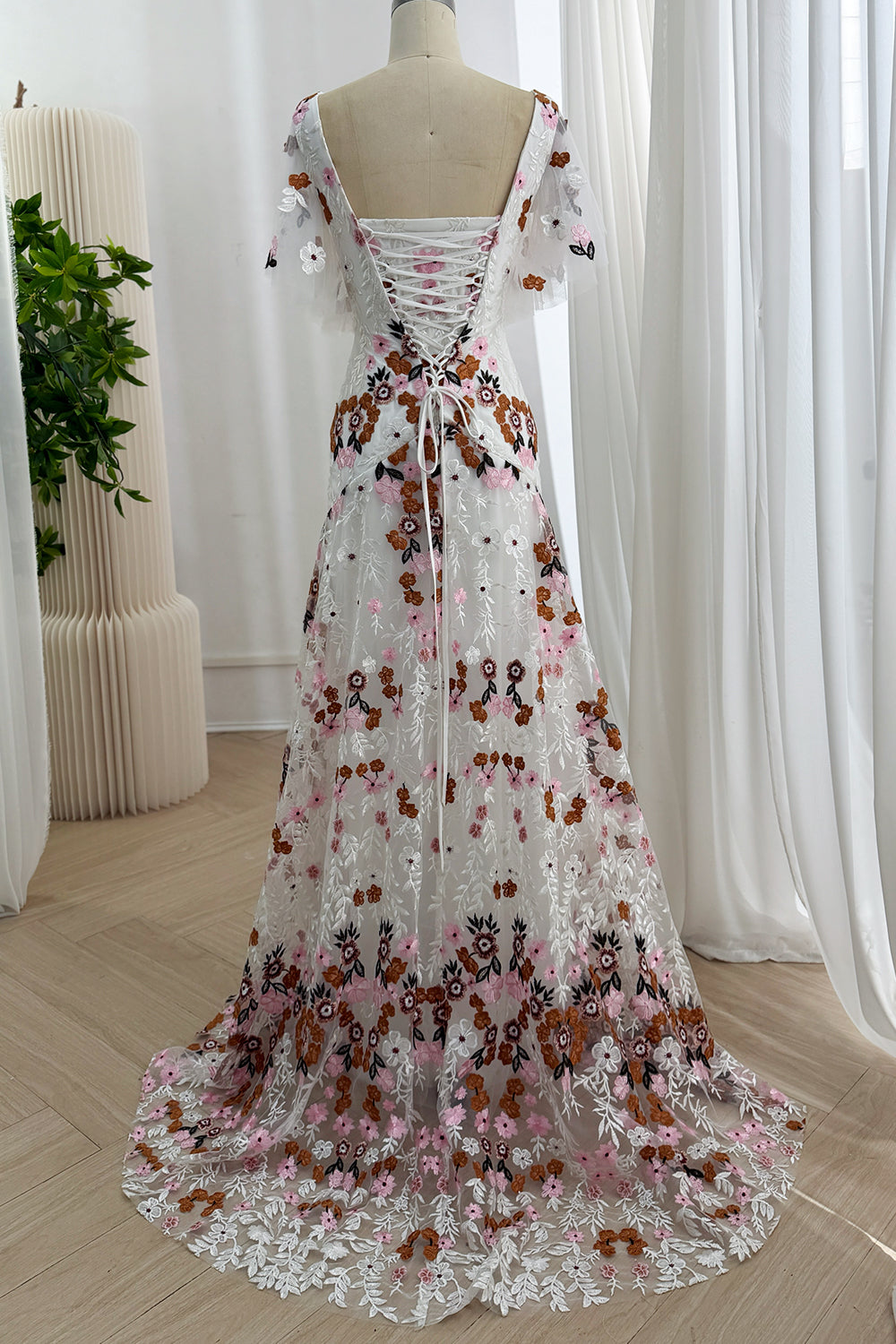 Full back view of the ivory floral embroidered gown with a corset back and sweep train