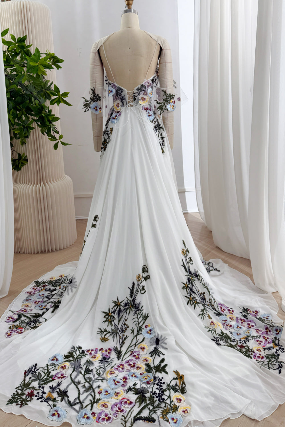 Back view of the ivory floral embroidered gown showing the low open back, corset lacing, and sweeping train