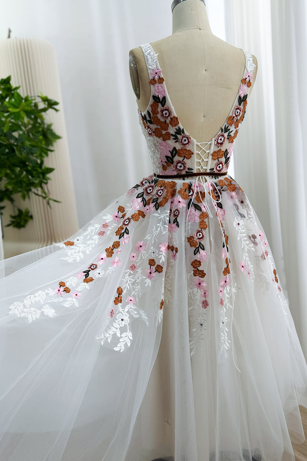 Back view of the ivory tea-length floral tulle dress with a low V-back, corset lacing, and gathered skirt