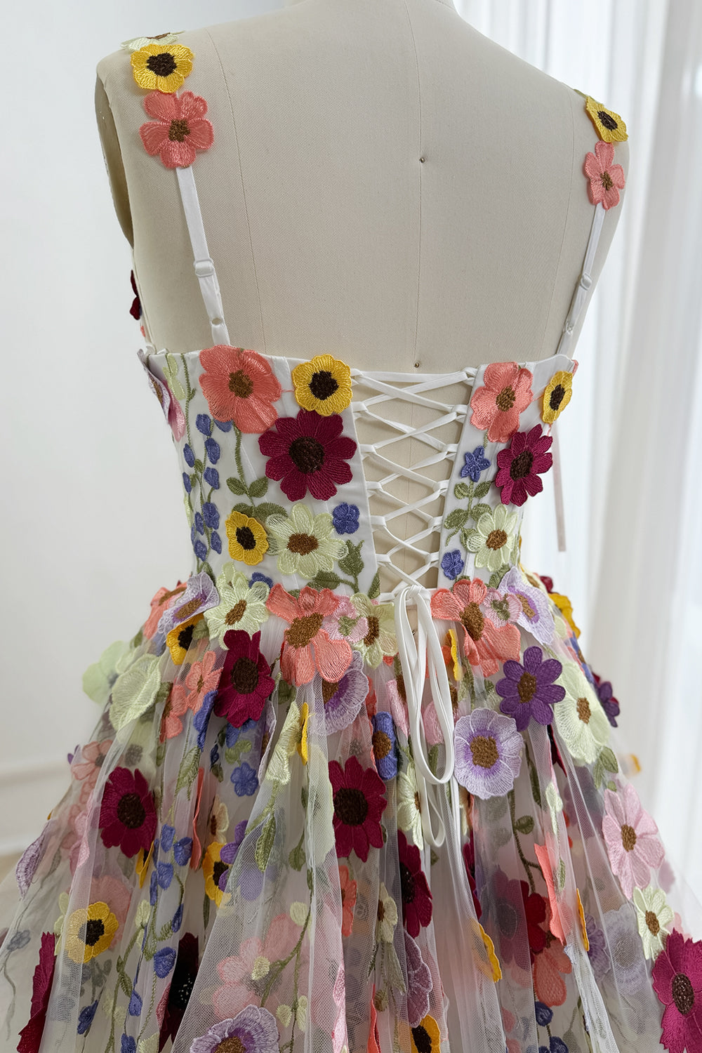 Close-up of the lace-up back and multicolor embroidered flowers on the gown
