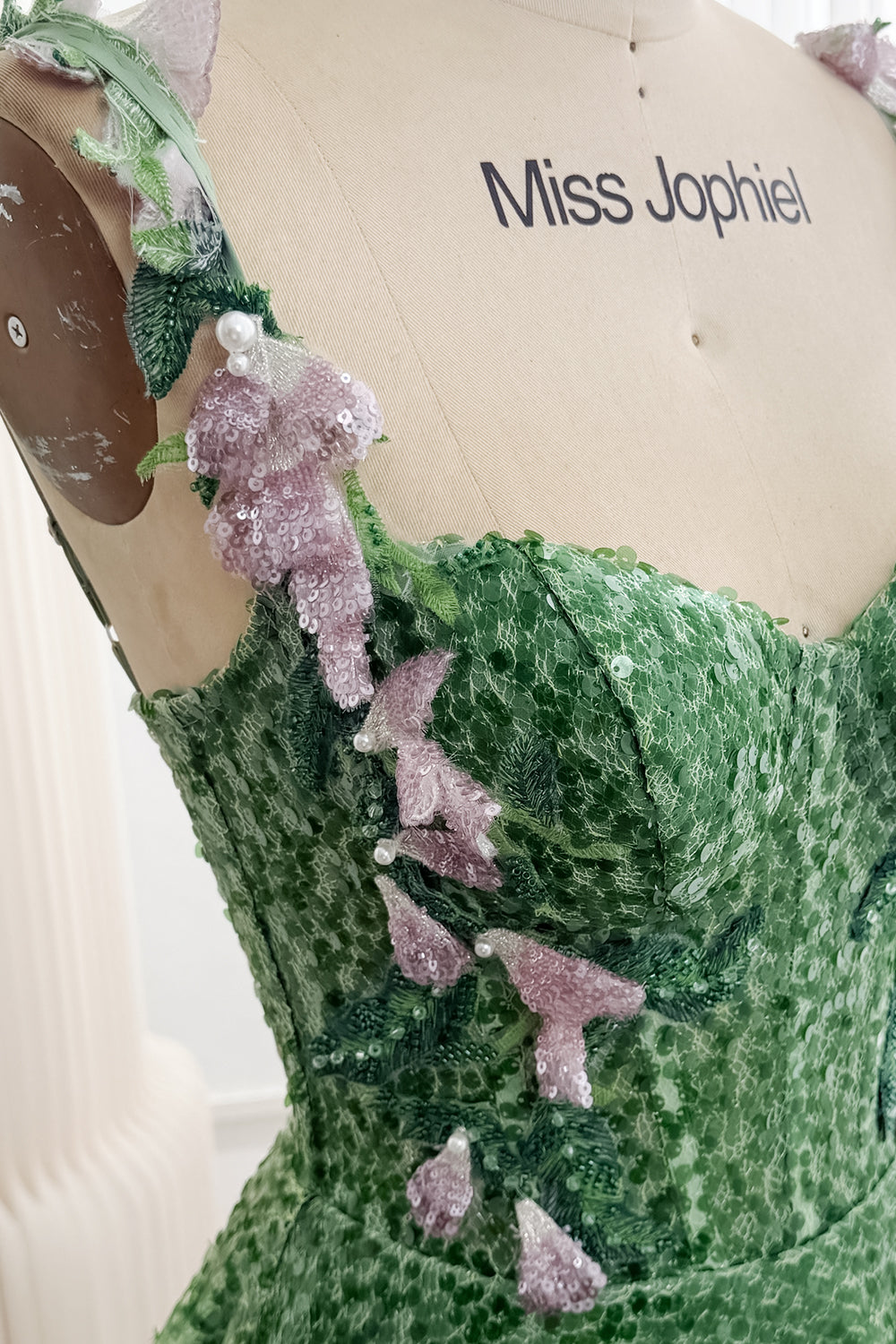 Close-up of pink sequined flowers and green leaf appliqués on gown bodice