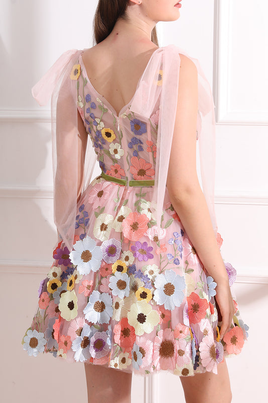 Back view of a pink floral embroidered mini dress showing the V-back, concealed zip, tulle bow shoulder ties, and green sash