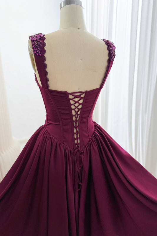 Back detail of plum dress showing corset lacing, embellished wide straps, pointed waist, and gathered skirt.