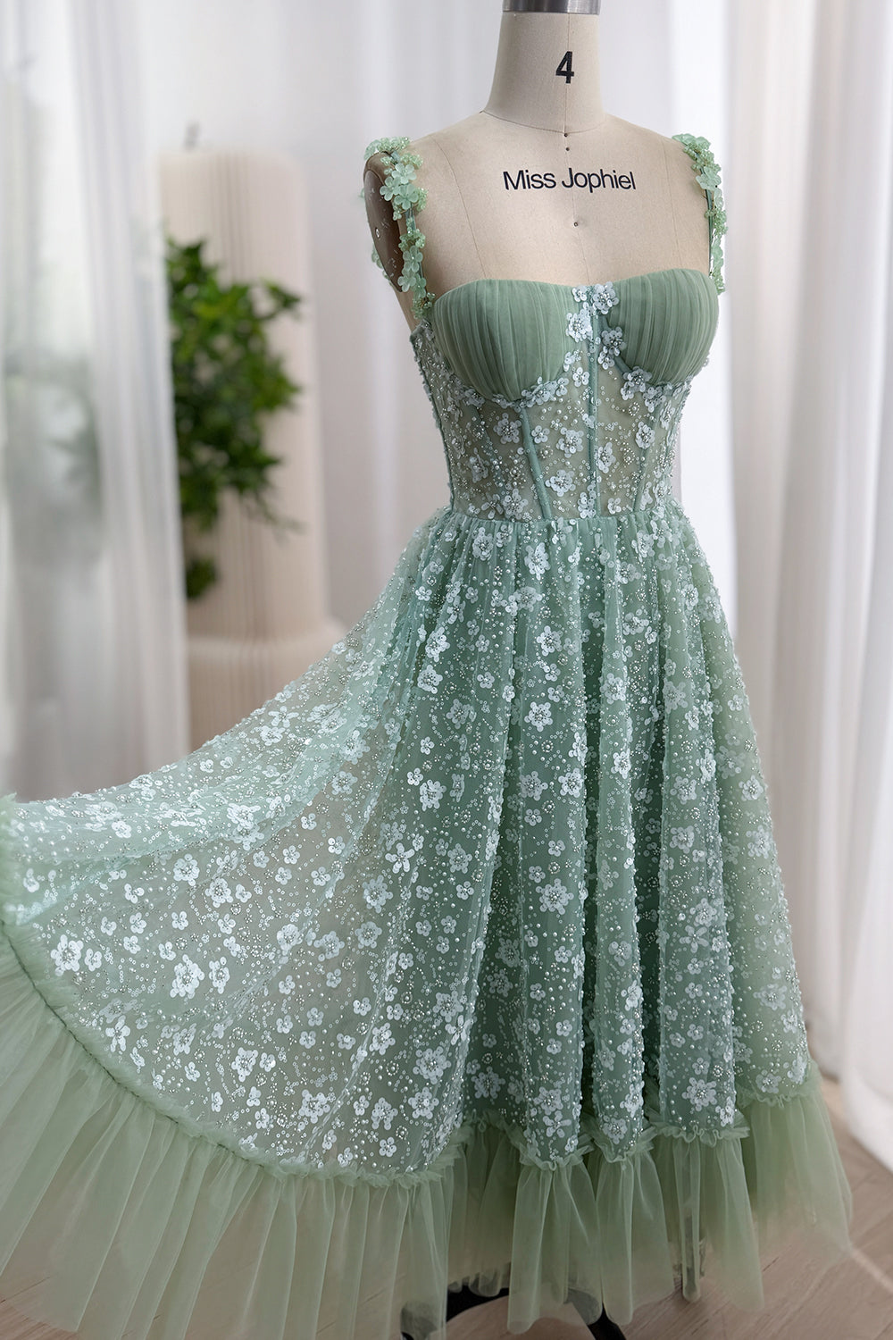 Three-quarter front view of a sage green tea-length floral sequin corset dress with a full A-line skirt