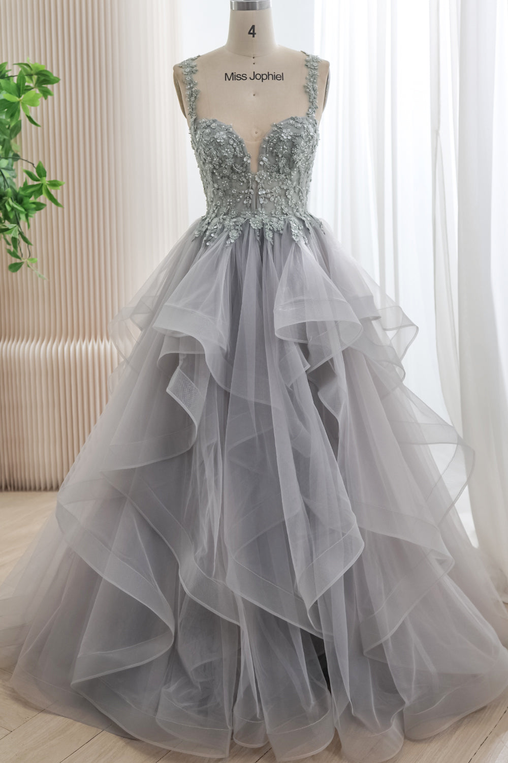 Front view of a silver-gray tulle ball gown with a floral beaded corset bodice, sweetheart plunge neckline, and cascading ruffled skirt.