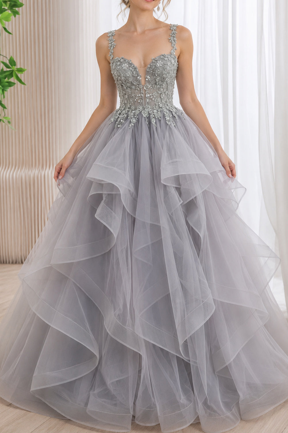 Model wearing a silver-gray floral beaded ball gown with a plunging sweetheart corset bodice and a voluminous cascading tulle skirt.