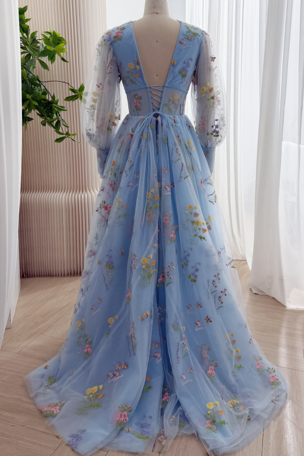 Back view of the sky blue floral tulle gown showing its lace-up corset back and train
