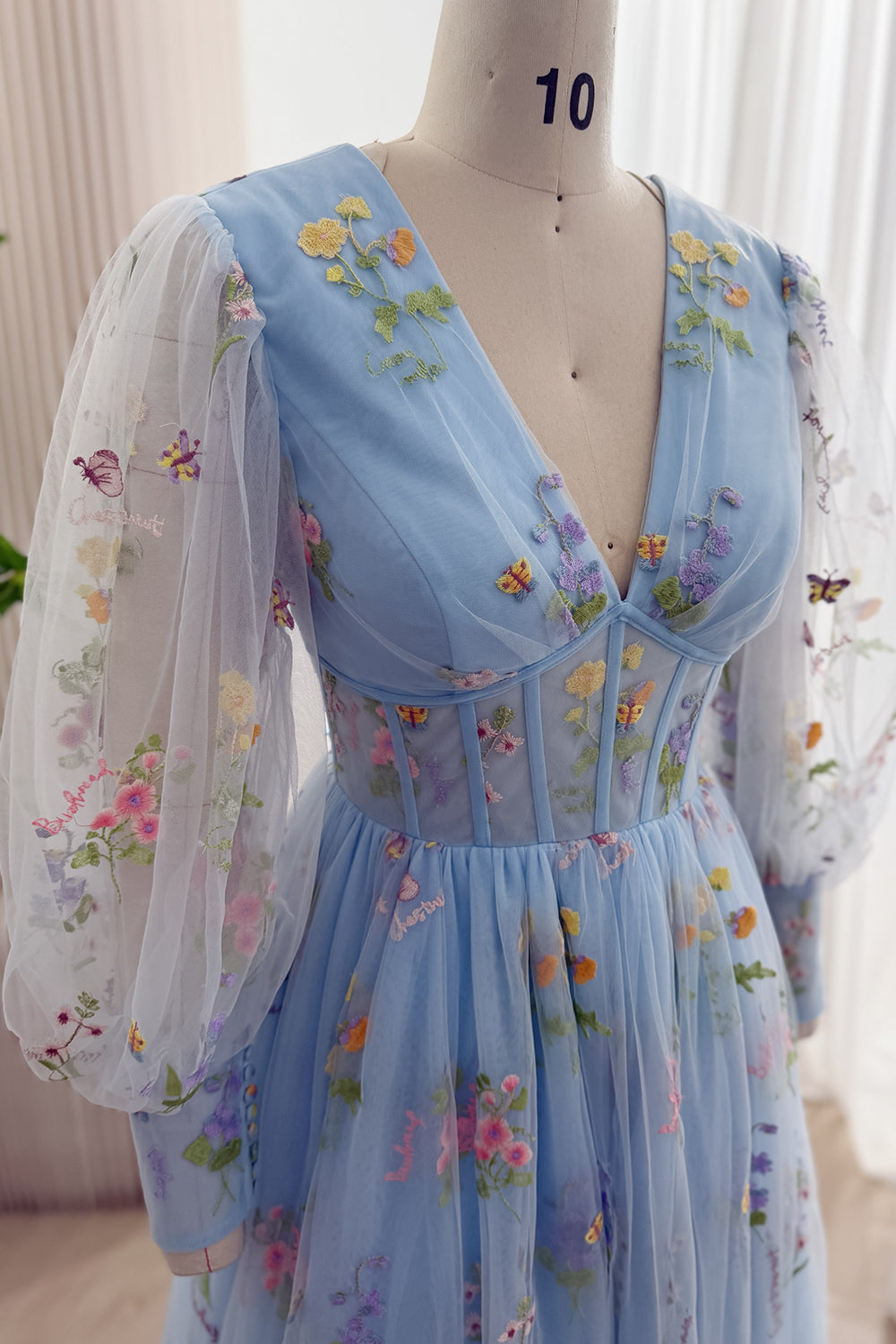 Close-up of the V-neck corset bodice and sheer floral embroidered sleeve on the sky blue gown