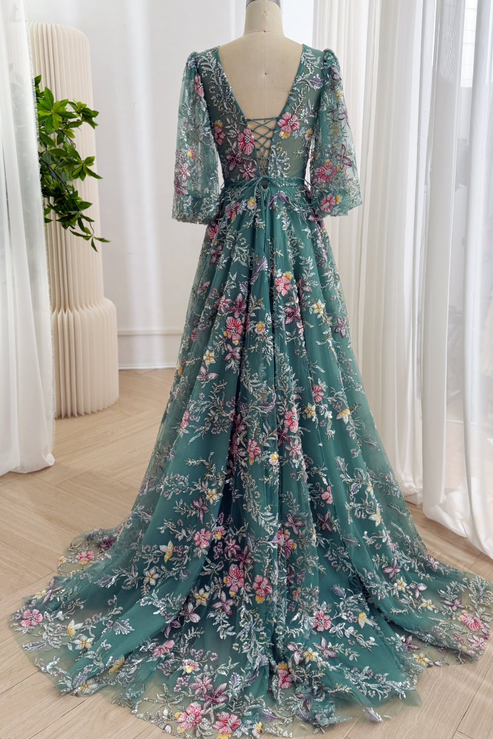 Full back view of the teal floral tulle gown with a low lace-up back, full A-line skirt, and embroidered chapel train