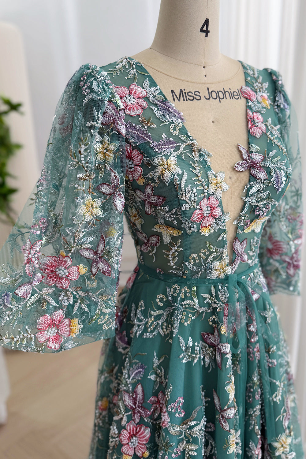Detailed view of teal tulle covered with multicolor floral embroidery, sequins, beading, and dimensional appliqués