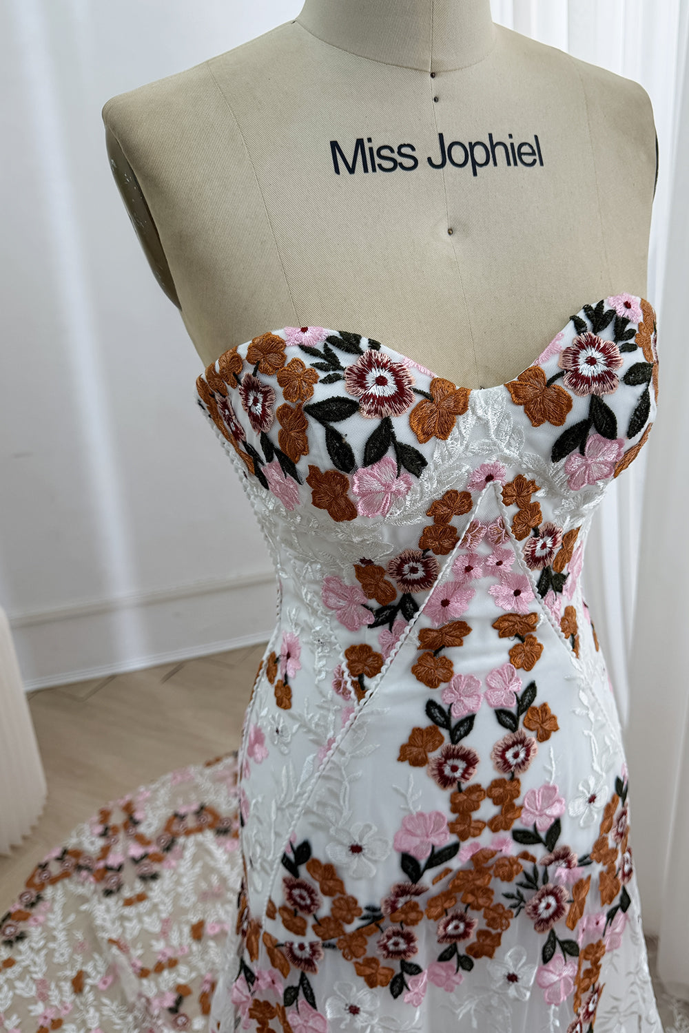 Close-up of the white corset-inspired bodice with pink, brown, burgundy, and black floral embroidery