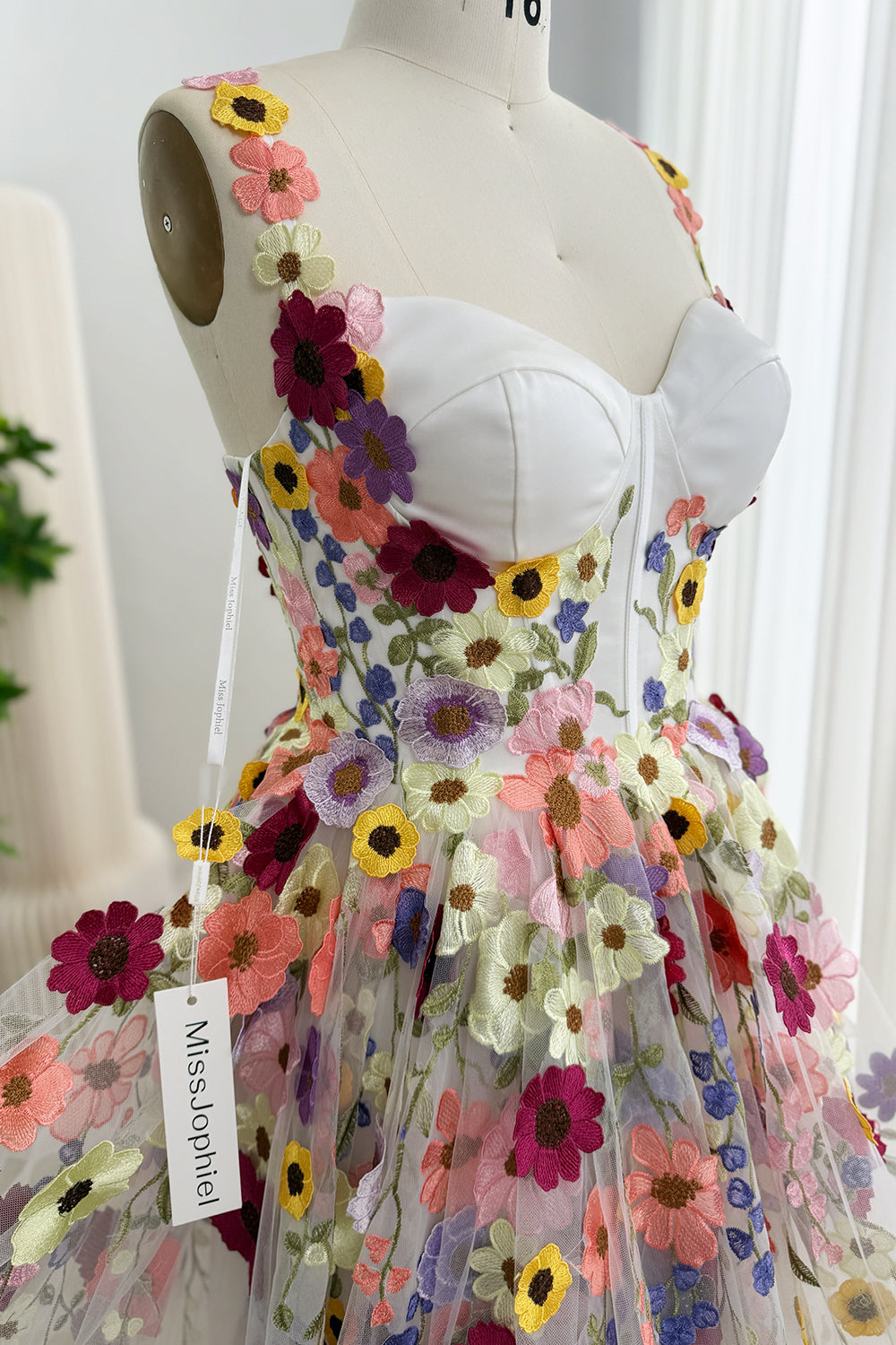 Angled close-up of the sweetheart bodice, flower-trimmed straps, and floral embroidery