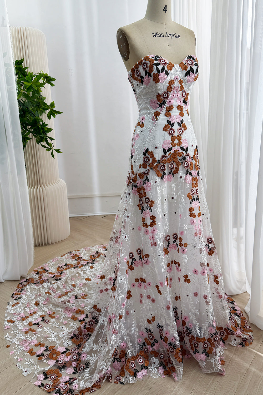 Front view of a white strapless floor-length wedding dress with multicolor floral embroidery and a long train