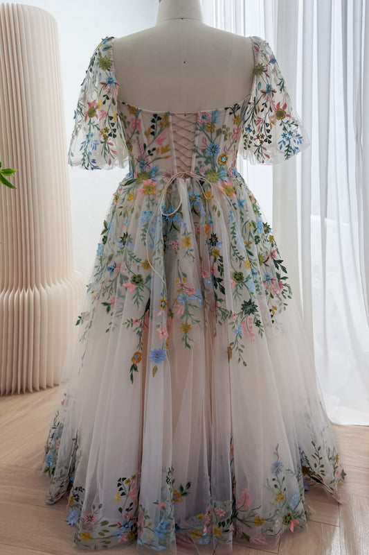 Back view of a floral embroidered tulle gown showing the lace-up corset back, sheer puff sleeves and floral embroidery along the hem.